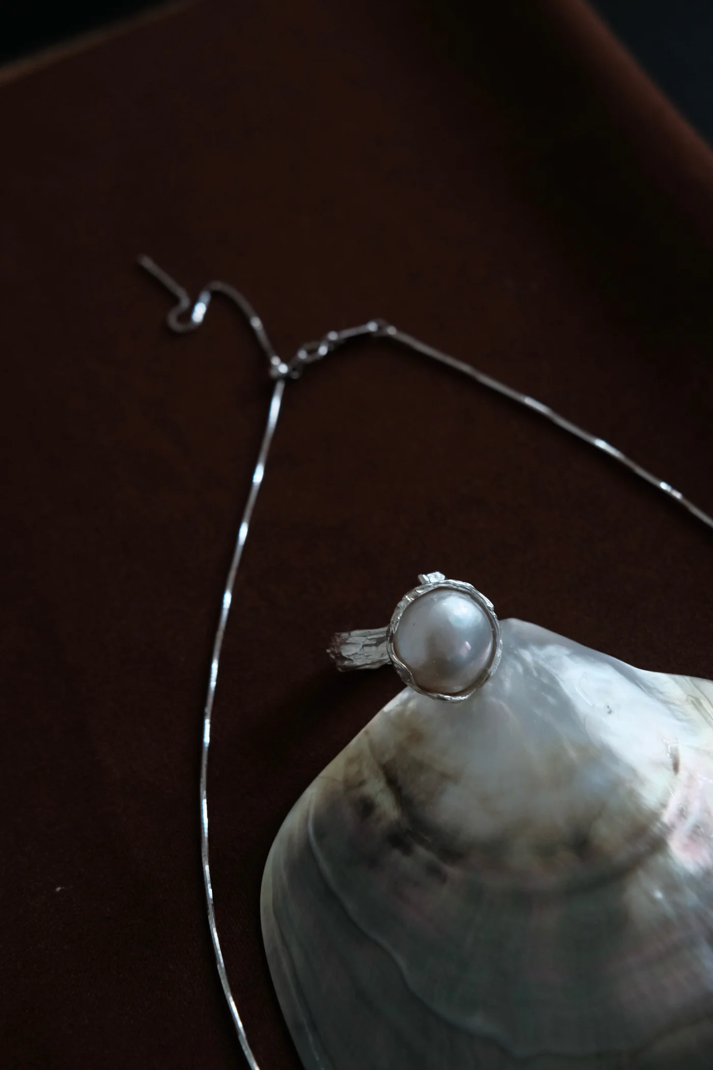 JUPLE pearl necklace on rich brown fabric